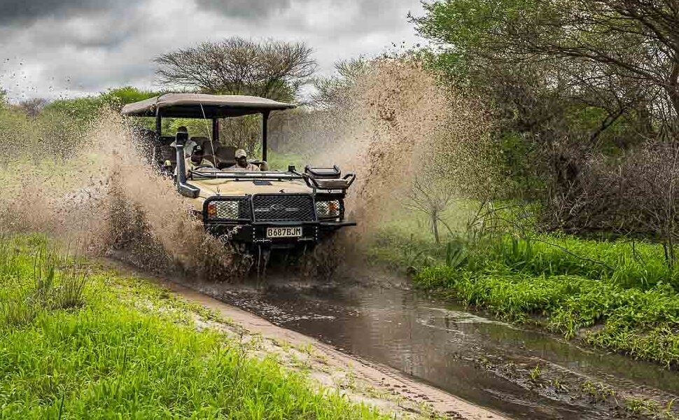 Driving Uganda rainy season safari tracks – 4x4 vehicle navigating a muddy safari track