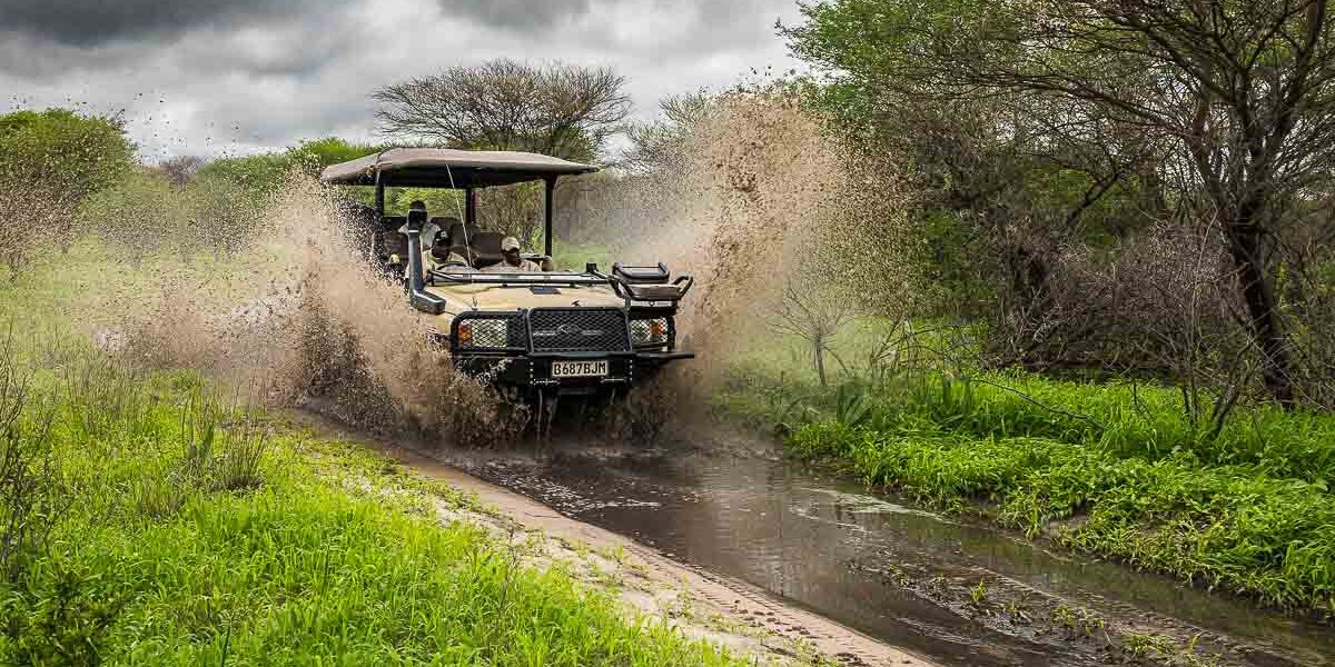 Driving Uganda rainy season safari tracks – 4x4 vehicle navigating a muddy safari track